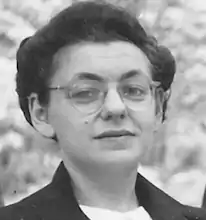 headshot of a young woman with glasses and short wavy dark hair looking straight into the camera