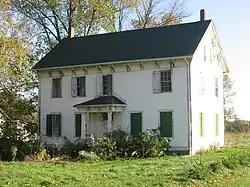 Color photo of an old, 2-story school building, painted white