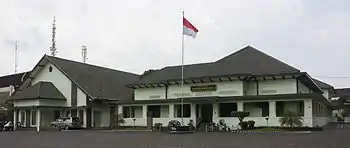 A photograph of a low building with a flagpole in front; its walls are painted green.