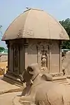 Small stone domed building, with a carved bull in the foreground