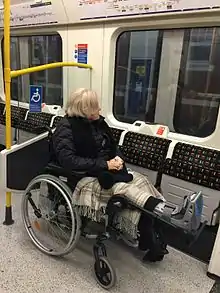 A photograph of a person in a wheelchair parked in the reserved space inside a tube train.