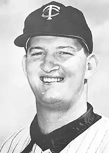 A man in a light baseball uniform and dark cap