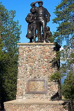 Three figures on a tall stone plinth