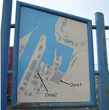 Sign showing buildings in the fjord harbour area with arrows added to point to the Dora complexes.