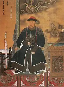 Three-quarter painted portrait of a thickly bearded man wearing a red hat adorned with a peacock feather and dressed with a long dark robe with dragon patterns. Clockwise from bottom left to bottom right, he is surrounded by a sheathed sword mounted on a wooden display, Manchu writing on the wall, a three-clawed dragon and a five-clawed dragon (also printed on the wall), and a wooden desk with an incense burner and a book on it.