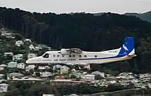 A small plane flies over a wooded, residential area.