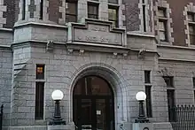 The main entrance to the First Battery Armory, a large granite arch flanked by lampposts