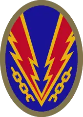 Oval shaped shoulder patch with a deep blue background. Lightning bolts break a yellow chain, representing the liberation of Nazi-occupied Europe.