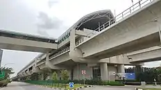 The station exterior along the road, with an overhead bridge connecting the station to the bus stop on the other side.