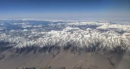 Aerial view from the east of the Eastern Sierra with Mount Whitney.  The snow-capped mountains drop steeply to dry desert on the east side.