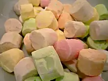 A pile of small cylindrical pieces of confectionery each one a different pale pastel colour