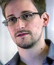 A small-bearded caucasian man wearing glasses