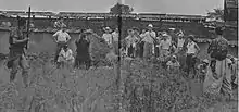 Film makers stand in front of actors while filming the movie.