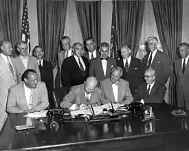  Eisenhower seated at the desk surrounded by 12 men