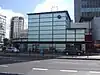 A light blue building with a dark blue sign reading "ELEPHANT & CASTLE STATION" in white letters all under a blue sky with white clouds