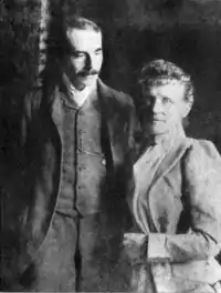 Nineteenth century photograph of a man in his 30s and a middle-aged woman standing side by side. He has a large moustache, and is looking at the woman; she is looking straight at the camera.