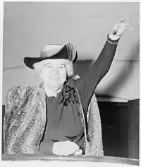 Photo of Elizabeth Kenny 1950, with short white hair, smiling and waving