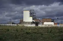 Headstocks and industrial buildings with a field in the foreground