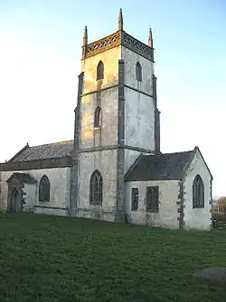 Whitewashed building with square tower.