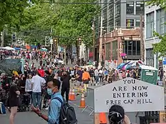 Crowded street, with barricades and a sign