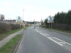 Open road in countryside, entering a residential stretch with speed limit