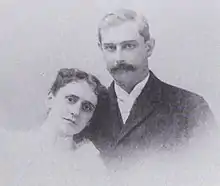 A black-and-white photographic portrait of a man and woman from the shoulders up