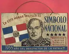 A metal sing with an engraving of Trujillo and the text "En este hogar Trujillo es simbolo [sic] nacional".