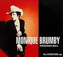 The left half depicts the artist on red background. She wears a cowboy hat and a dark suit. She is crouched down on one knee with her head turned to her right. Her name is in large print near the bottom of the cover. The right half has a black background with white print. Below her name is the lead track, "Wrecking Ball", below that is the title, the Eventide ep.