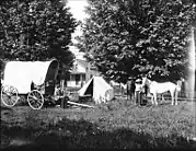 Ezra Meeker's camp with covered wagon, tent, and horses, Oregon, c. 1913