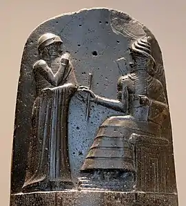 Hammurabi (left), depicted as receiving his royal insignia from Shamash (or possibly Marduk). Hammurabi holds his hands over his mouth as a sign of prayer (relief on the upper part of the stele of Hammurabi's code of laws).