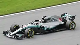 a grey open wheeled racing car is driven around a track