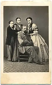 Conde de Lipa sits on a chair, in company of his son, daughter, and wife