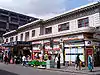 A white building with a sign reading "FARRINGDON & HIGH HOLBORN STATION" in gold letters and people in front all under a blue sky with white clouds