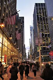 Skyscrapers line a busy sidewalk along 6th Avenue in New York City