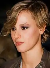 An image of a light brown-haired Caucasian woman in her early 20s. She is wearing a brown leather jacket.