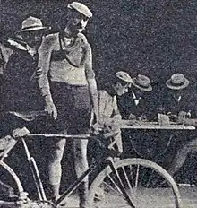 Image of a man in cycling gear standing behind a bike