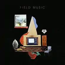 A black square with the words "Field Music" in grey text at the top. Beneath the text is a graphic, in the centre of which is a television inside a box with a large triangle resting atop of it. Beneath the television is a brown-patterned carpet with pillows and pieces of cloth scattered around it. To the right of the television is a blue chair and a brown door. Above the door is the shape of white arrow pointing downward, with the words Open Here in black text within it. Above and to the right of the television is a window, through which an outdoor view and distant buildings are visible.