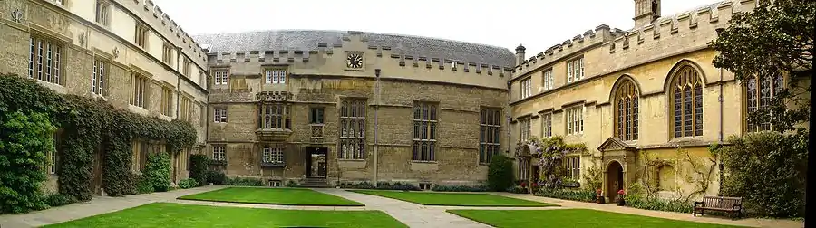 A panoramic view of the First Quadrangle of Jesus College. The hall is in the centre (at the west of the quadrangle), on the right-hand of the passageway leading through into the Second Quadrangle, and lit by three large windows. The Principal's Lodgings are on the north side of the quadrangle, between the hall and the chapel.