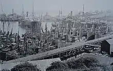 Many fishing boats and several large ships moored in a dock