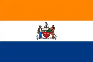 A flag of three horizontal colors is shown: orange on top, then white, and blue. At center is the coat of arms shown in the infobox image.