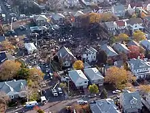 A black debris hole in the middle of a suburban neighborhood in Rockaway Park: The hole is surrounded by houses.