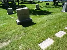 Grave monument in a field in front of a lake, inscribed "Folwell". Three or four graves visible, "Wm W. Folwell/1833–1929" at right.