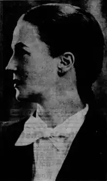 Photograph of a woman with dark, slicked-back hair, looking to her right. She is wearing a dark jacket and white bow tie.