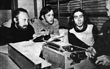 Four FLH members seated at a small table with a typwriter. Néstor Perlongher is on the right.