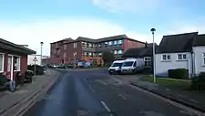 A road between some buildings leading up to a large hospital building