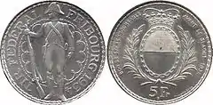 At left, the obverse of the silver-colored thaler, featuring a standing soldier looking left, a rifle in his right hand, surrounded by the inscription TIR FEDERAL FRIBOURG 1934. At right, the reverse, showing an oval form of the Fribourg coat of arms encircled by laurel branches, with a crown above. Along the outer edge is the inscription BON DE 5Fr REMBOURSABLE AVANT LE 31 AOUT 1934, with 5 FR at the bottom.