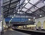 The interior of a building with white walls, white flooring, and a railway track running down the middle of the corridor with a train on it