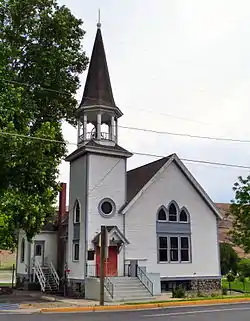 Photograph of the Full Gospel Church, a white, wooden church with a tall steeple and Gothic-peaked windows