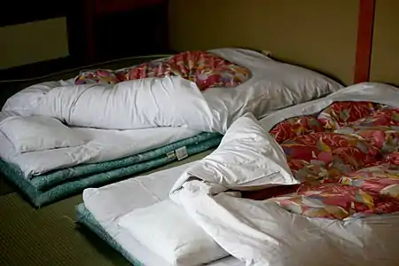 Each of these futon beds has three mattresses and a sheet-covered duvet, stacked directly on the tatami-matted floor. Japan