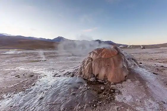 The vent is a small steaming cone with a polished appearance in an unvegetated landscape
